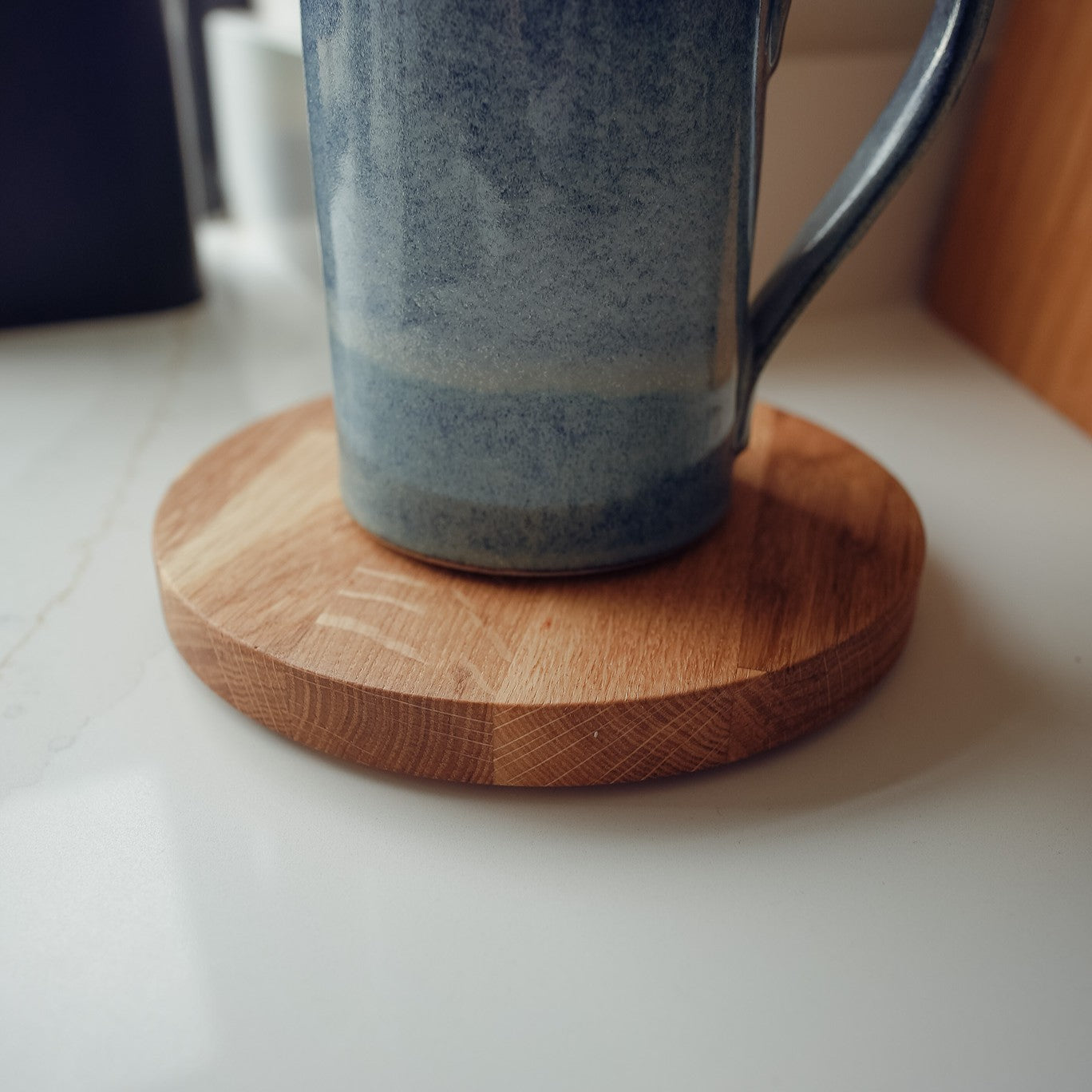 Blue mug on a large wooden mat on a white surface
