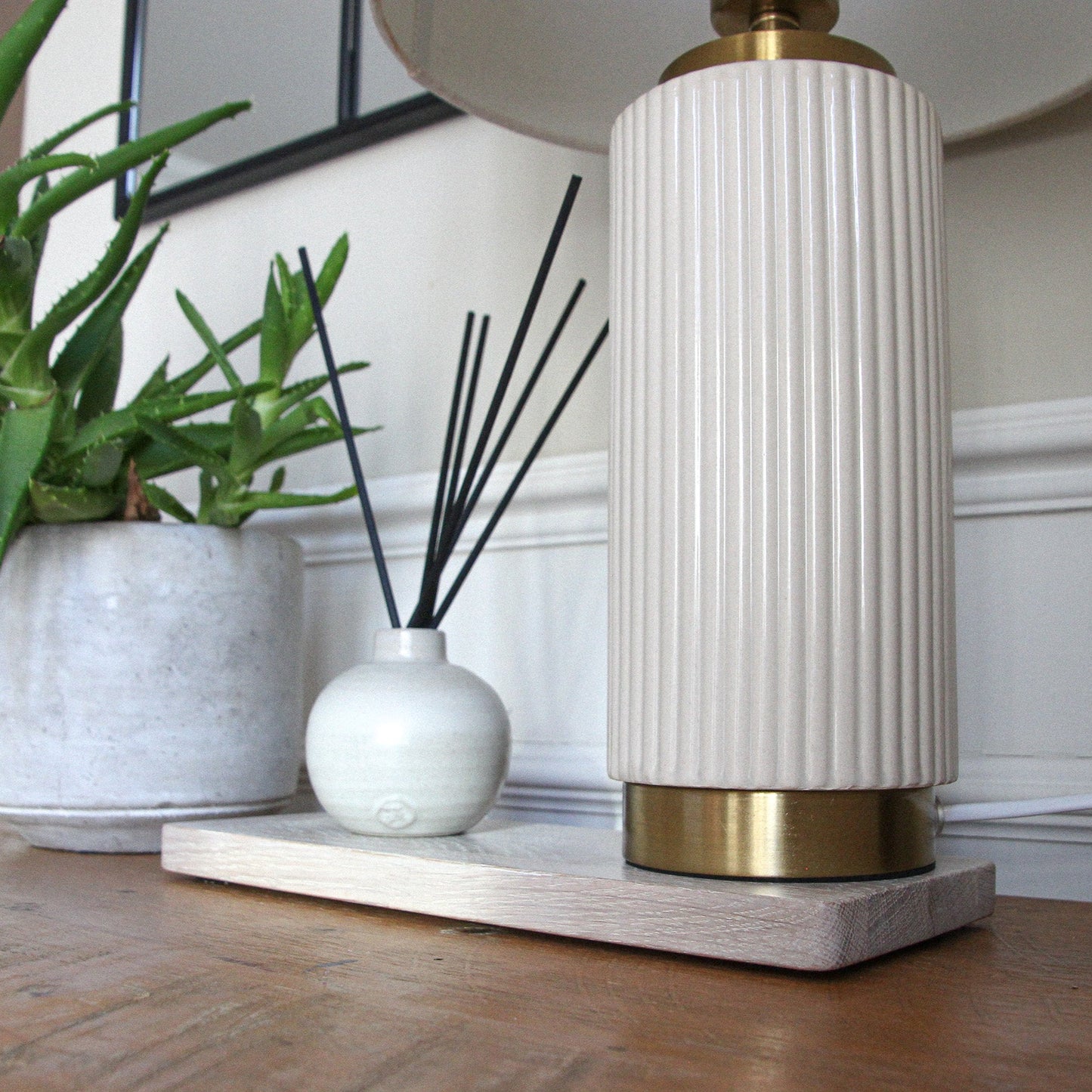 Decorative setup with a white lamp, diffuser, and plant on a light oak wooden mat in a rectangular shape