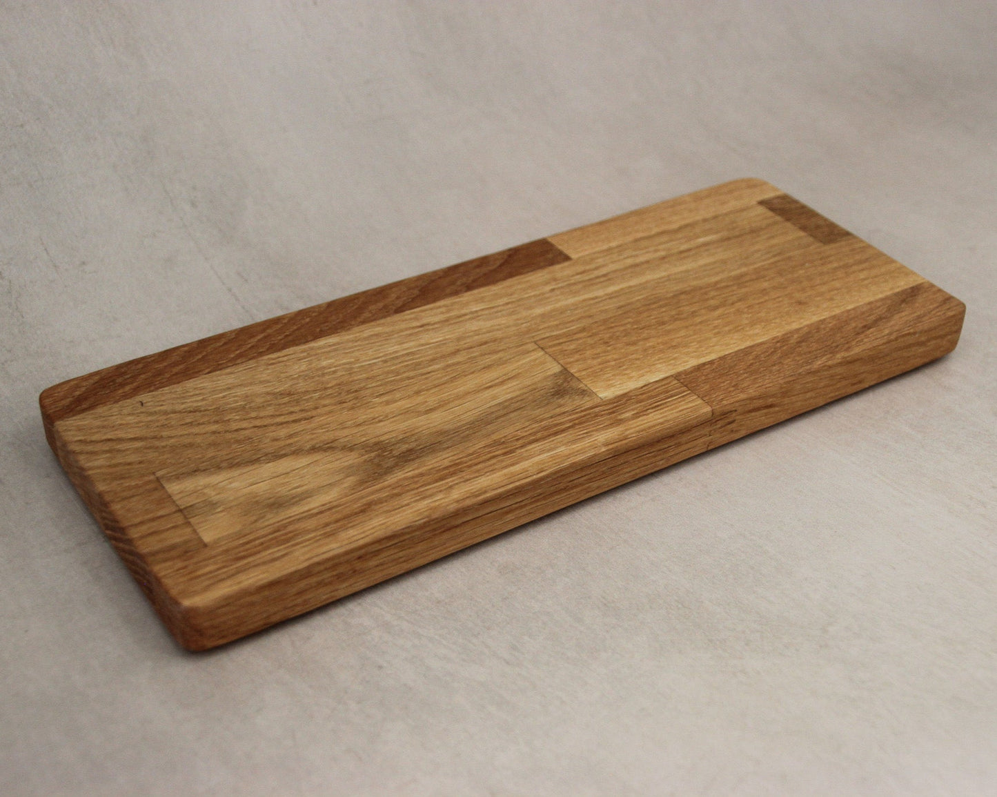 Rectangle long wooden cutting board on a beige surface