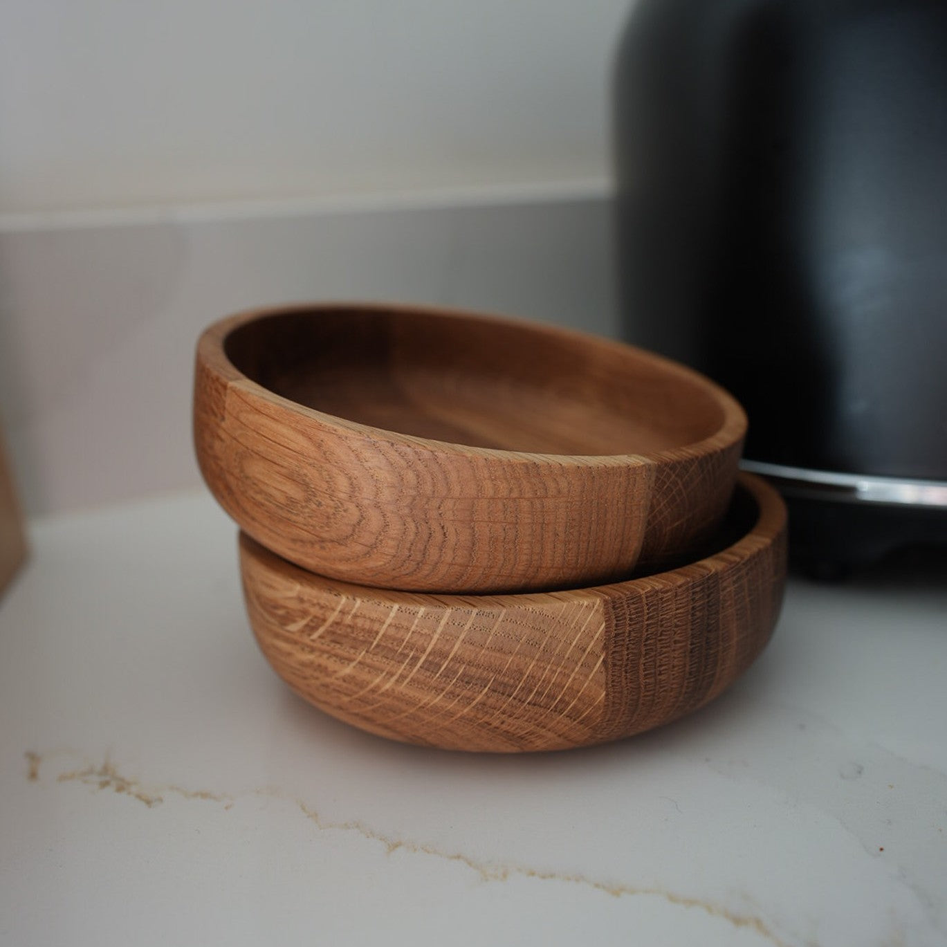 Two hand-turned oak bowls, stacked together, showcasing the rich grain and warm hues of the wood.