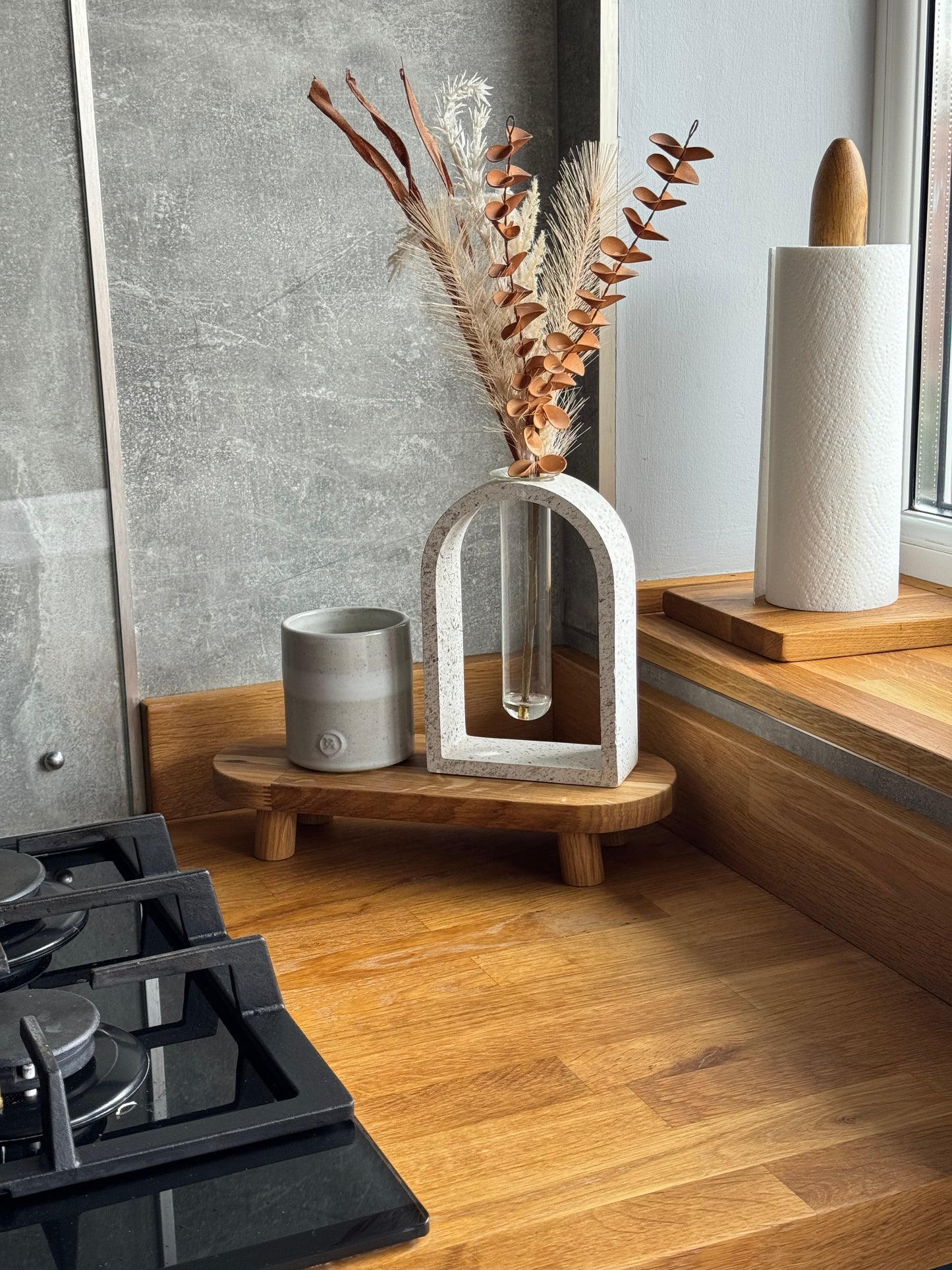 This home styling plant pot stand is pictured with a candle and dried flower arrangement on top, you can clearly see the oiled oak risers mini legs like a very short table for that could be used to style a mantlepiece or sideboard. The riser is oblong with rounded edged and is finished with oak oil which brings out the grain of the natural wood.