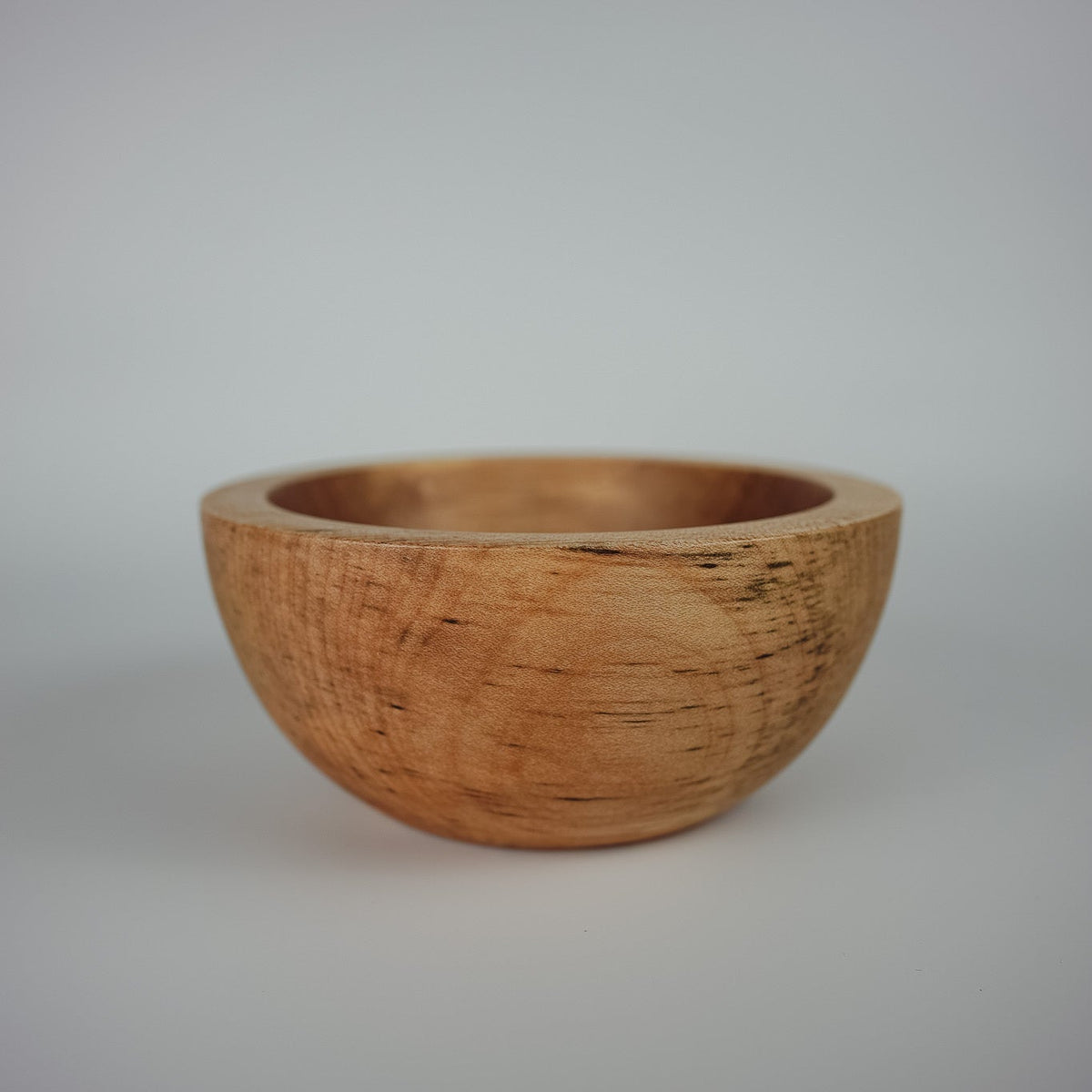 Decorative bowl made from sycamore wood on a plain white background