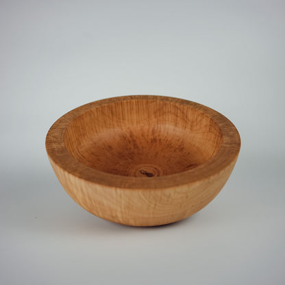 A thick and chunky handcrafted wooden bowl with a visible natural wood grain pattern, photographed on a neutral light white background.