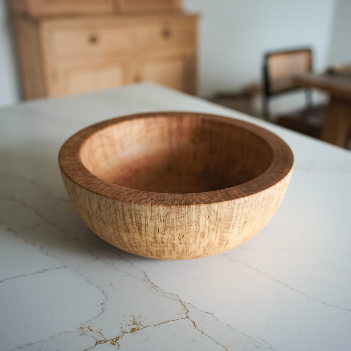 Large wooden bowl on white marble countertop, the bowl has very ticket edges and is very chunky