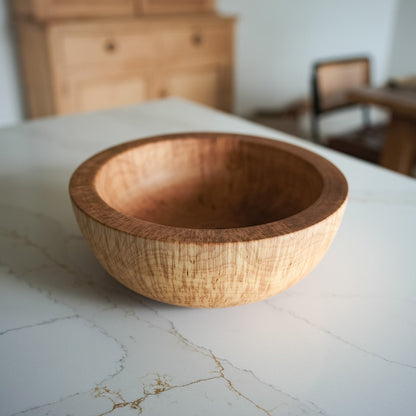 Large wooden bowl on white marble countertop, the bowl has very ticket edges and is very chunky