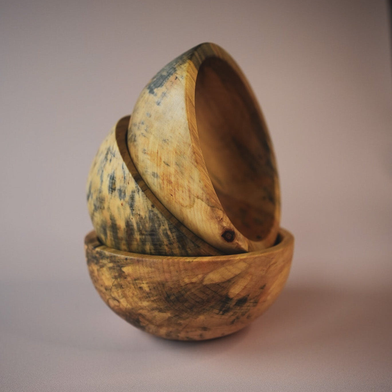 Three wooden bowls stacked on a gradient background