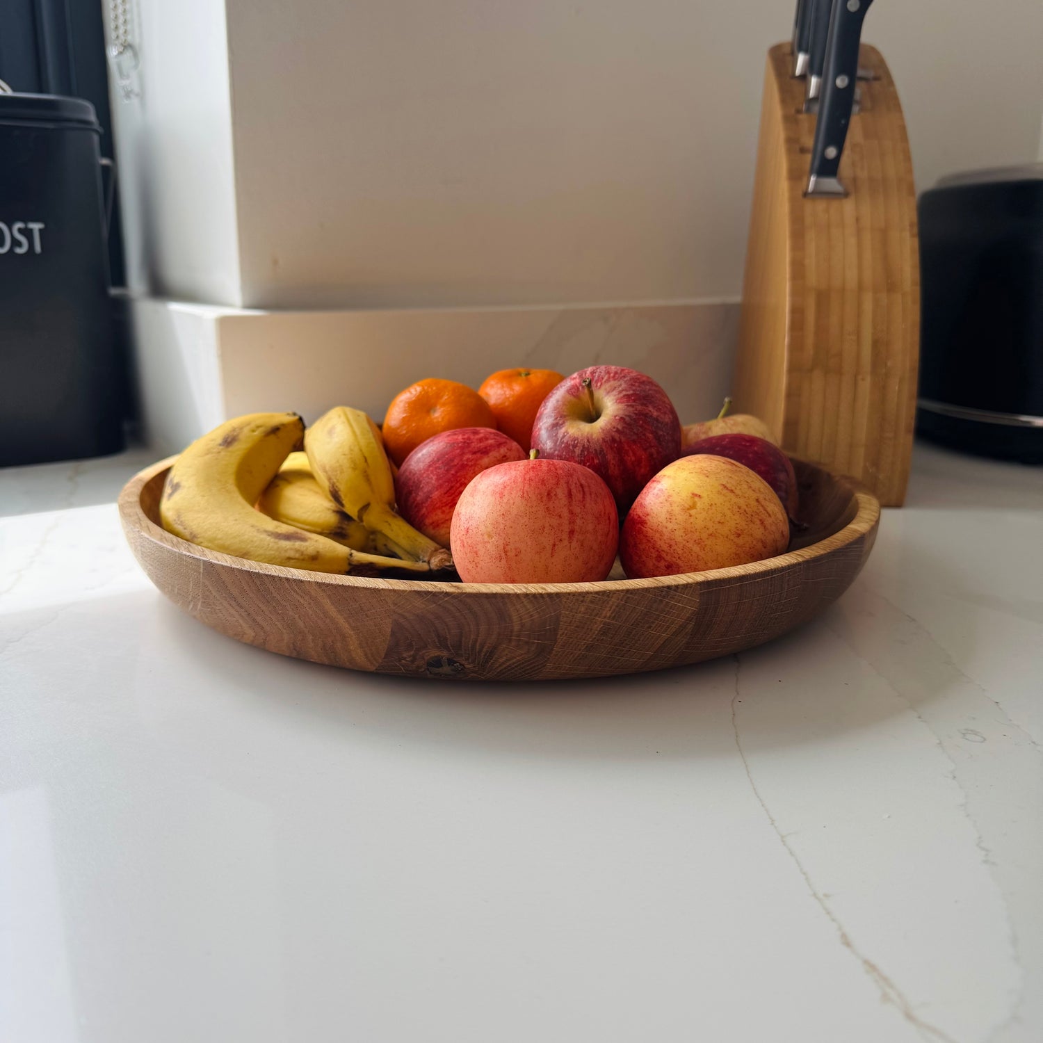Wooden/oak bowl with fruits on a marble kitchen counter