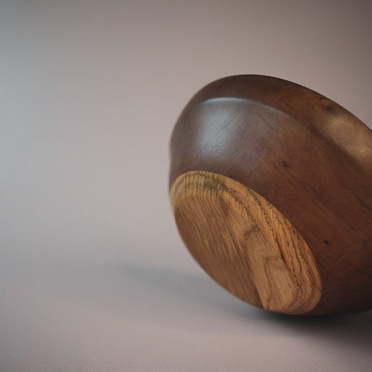 apple wood bowl with oak base on a plain background