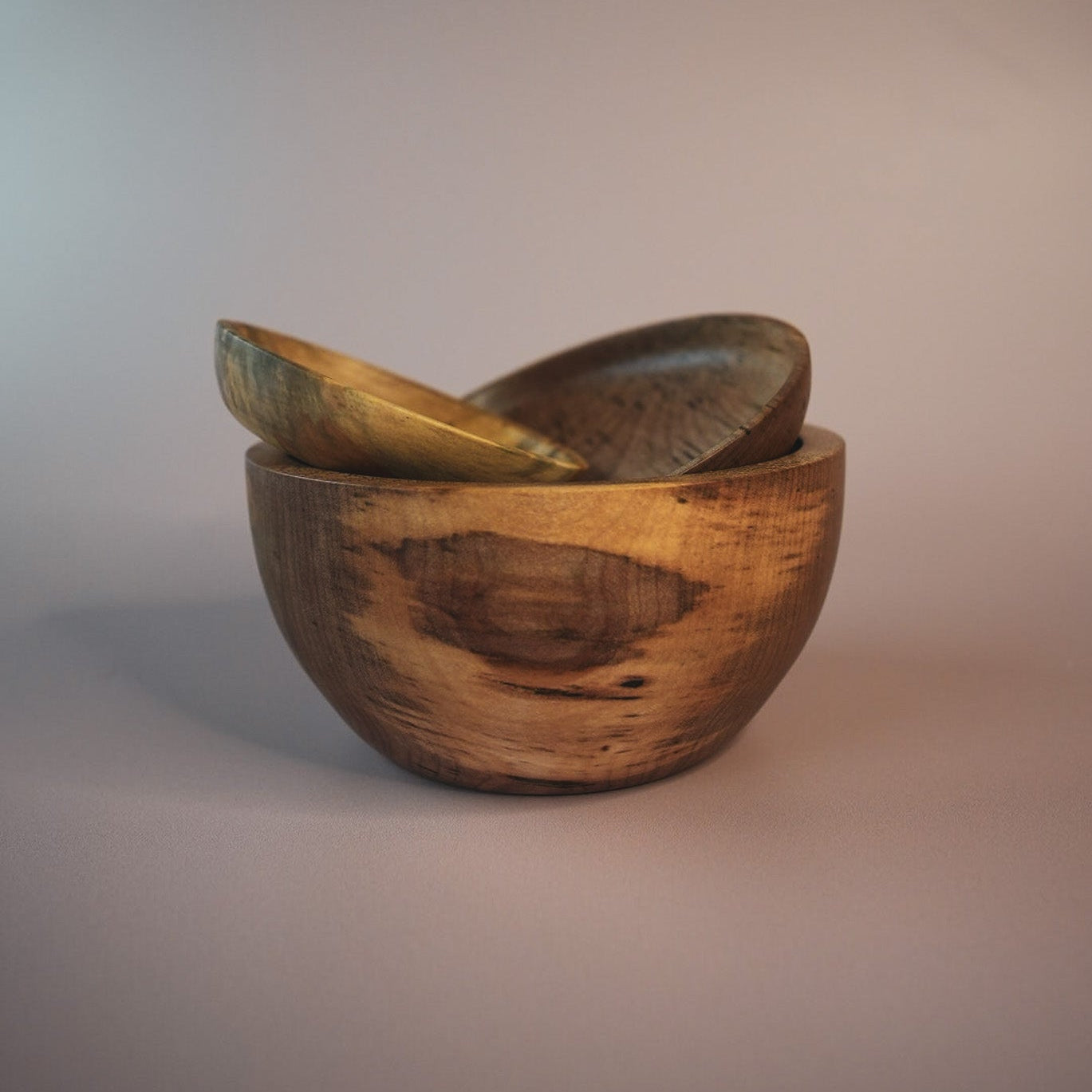 three wooden bowls stacked on a plain background