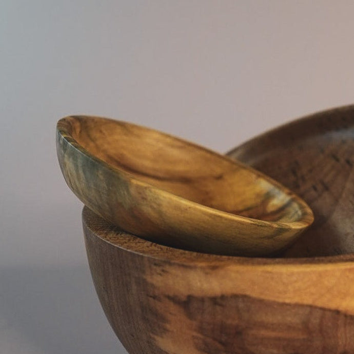 Three wooden bowls of varying sizes on a gradient background