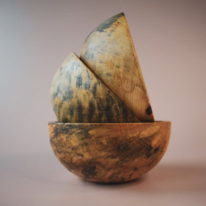 three wooden bowls stacked on top of one and other on a pink photography background